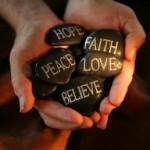 Photo of hands holding stones with spiritual messages written on them